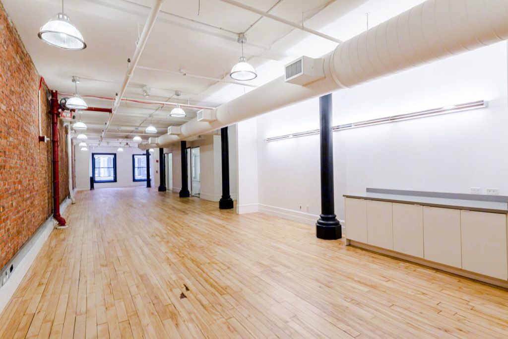 Long loft floor with exposed brick on one side and low white cabinetry on the other