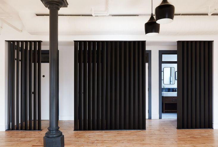 Black fluted partitions and pendant lights around a cast-iron column