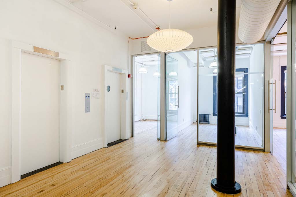 Glass-front offices beside a cast-iron column on a loft floor